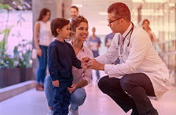 Médico pediatra conversando com criança e mãe